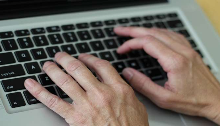 An individual typing on the keyboard.