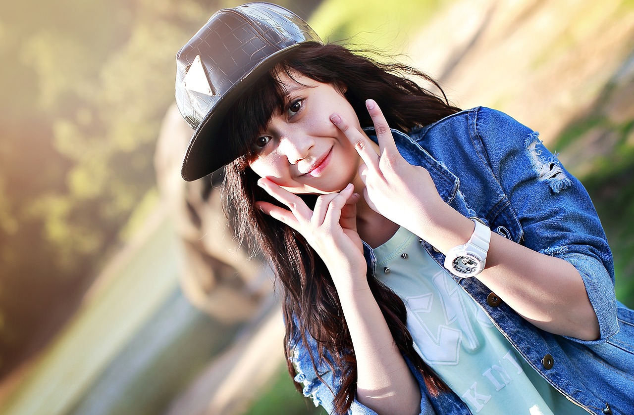 Young girl smiling and making the V Sign, Image by Jess Foami